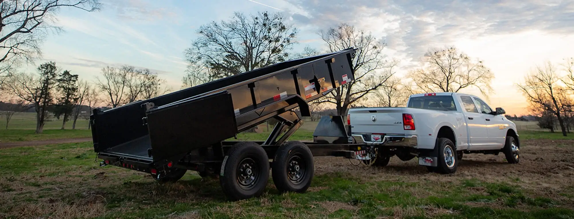 Truck towing a dump trailer at dusk
